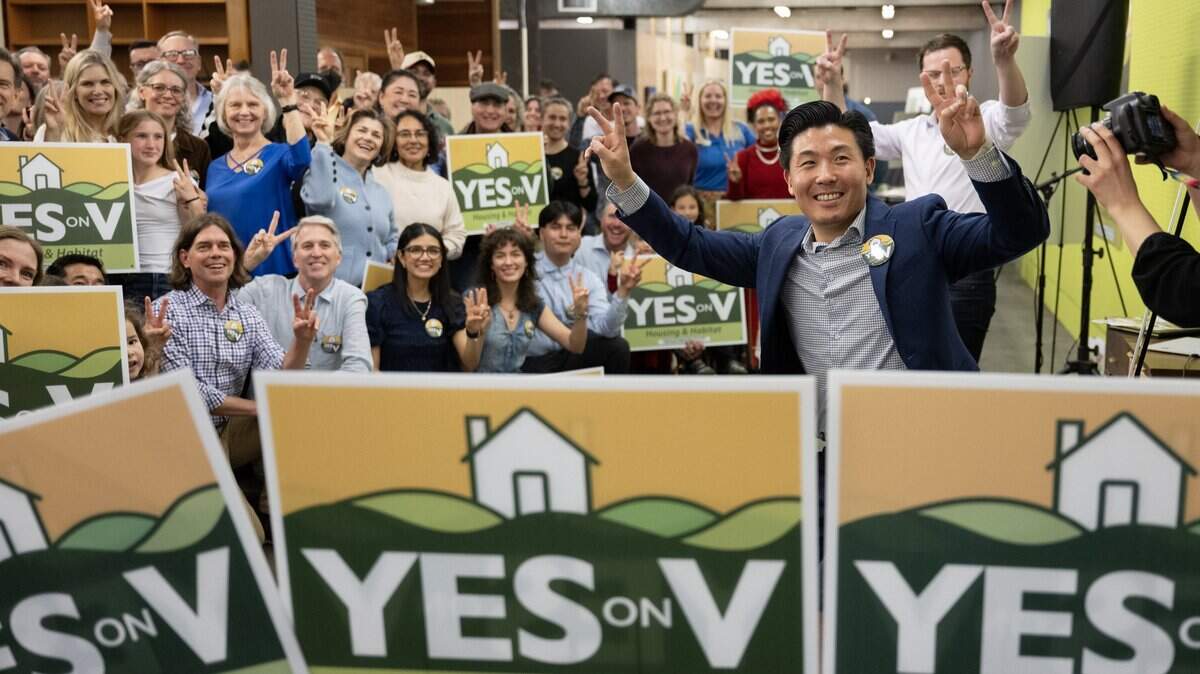 Campaign director Andrew Kim, right, and supporters of Yes on Measure V, flash victory signs at the kick-off rally in Davis on Wednesday, March 4, 2026. The measure to allow a 498-acre development with 1,800 homes on the city’s northern boundary has trailed since Election Night.