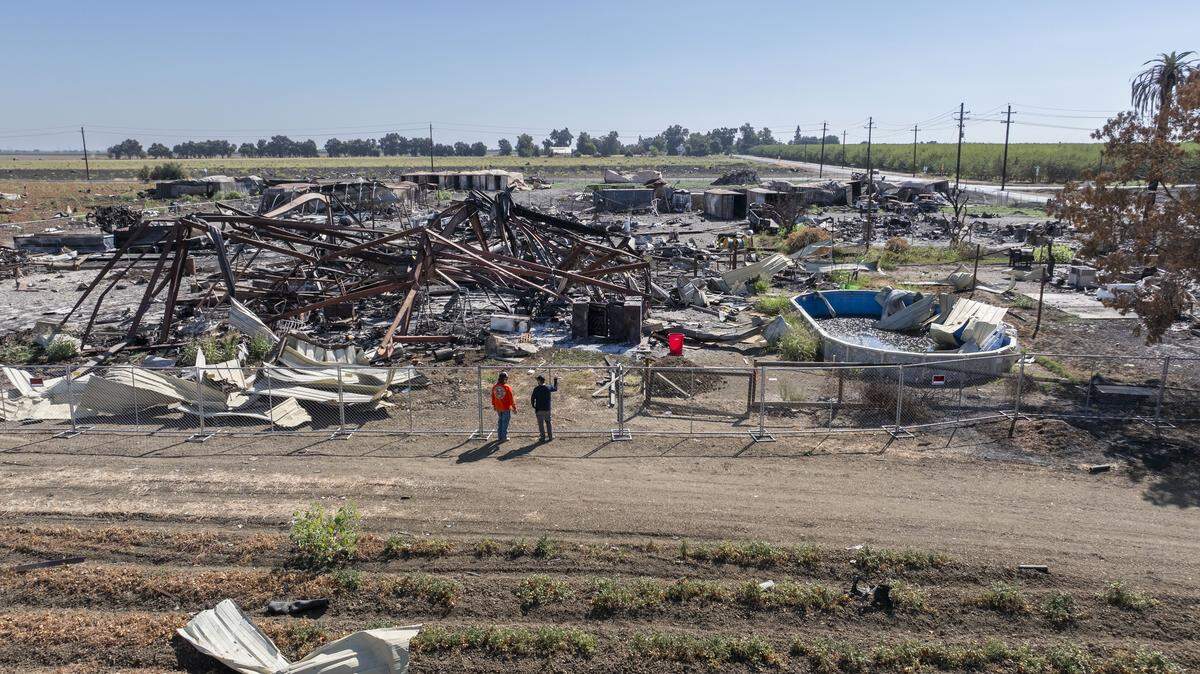 Jimmy Gerardo, of Vacaville, left, and his nephew Quinn Bonner, of Isleton, look behind a fence around the area of the former Esparto fireworks company on Thursday, Sept. 11, 2025. The area burned after an explosion in early July.