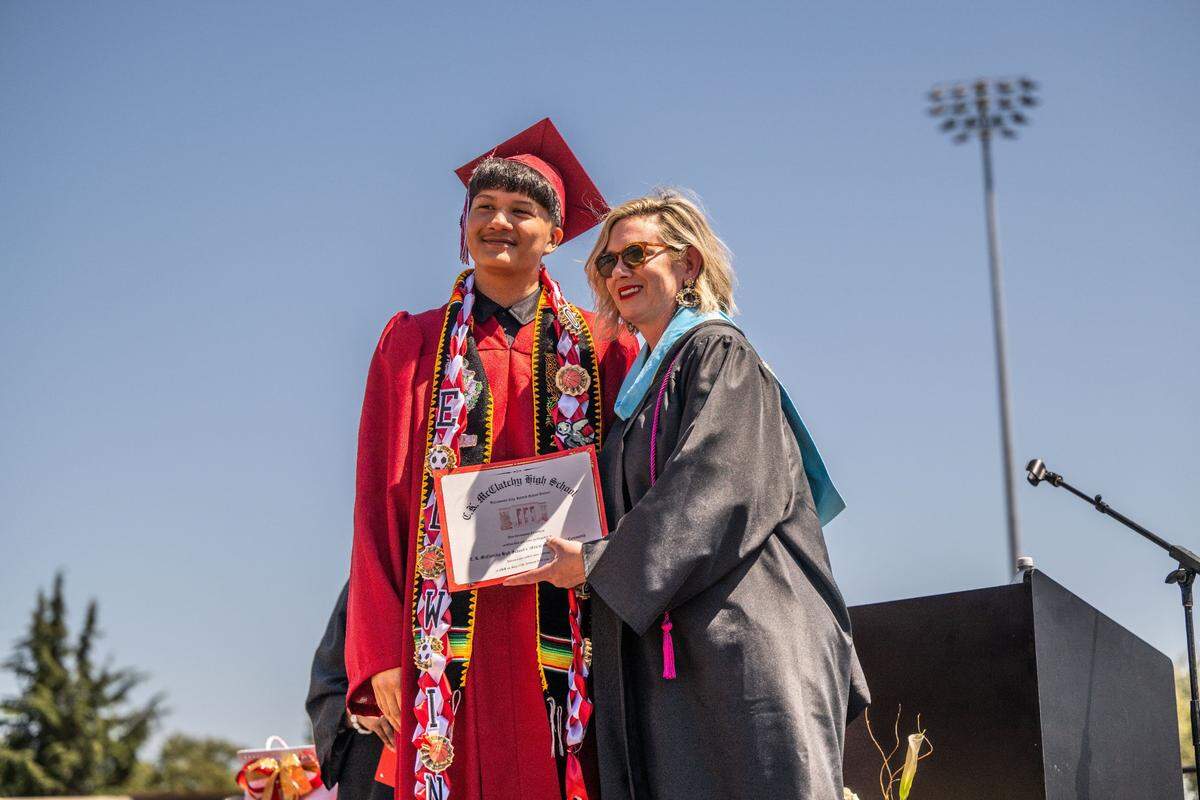 Edwin Rebollar stands for a photo with C.K. McClatchy Principal Andrea Egan as students take part in their commencement ceremony on Tuesday at Sutter Health Park.