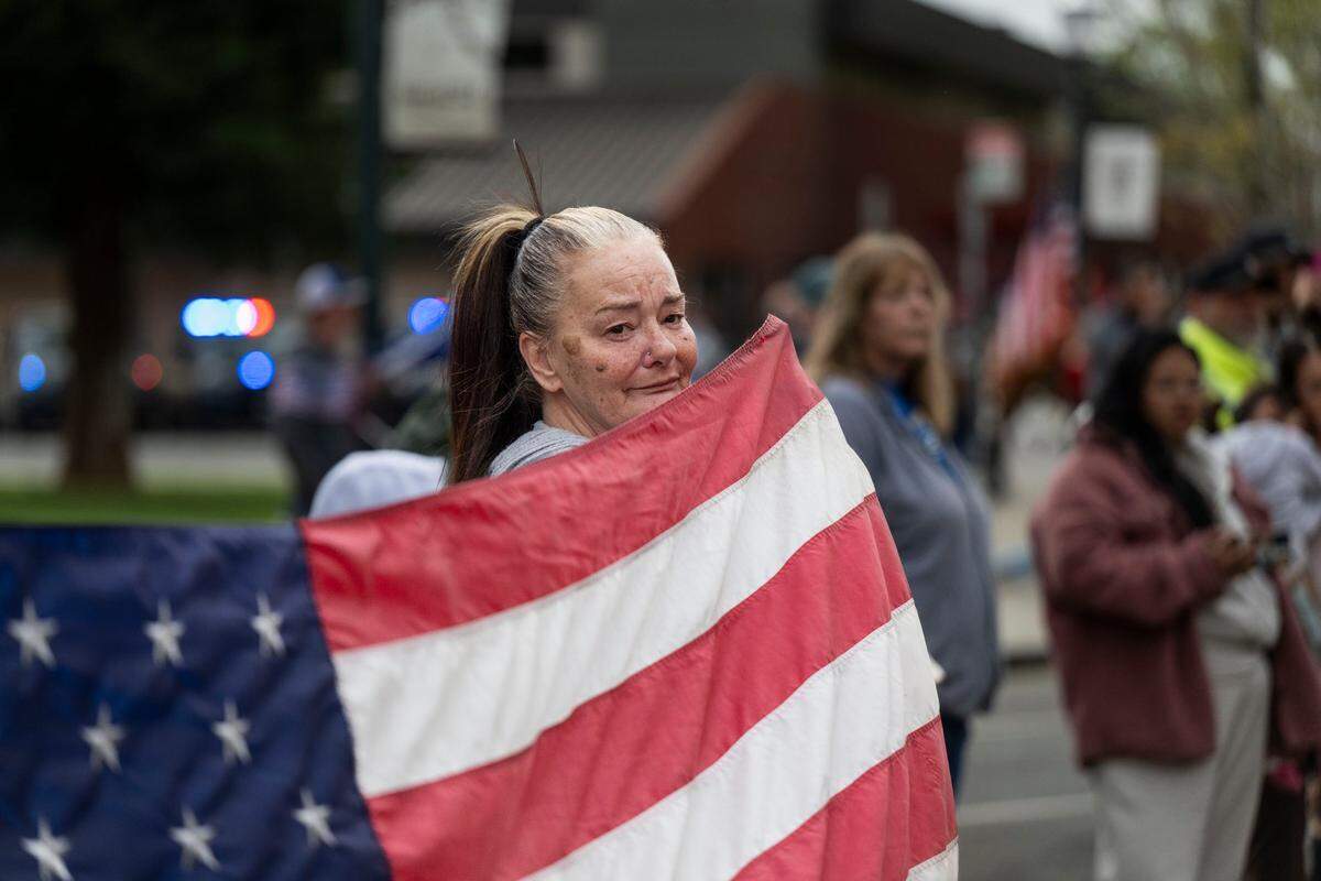 Marysville resident Jody Roope holds an American flag to honor fallen police officer Osmar Rodarte on Thursday during a procession through the city from the Lakeside Colonial Chapel to Placer County.