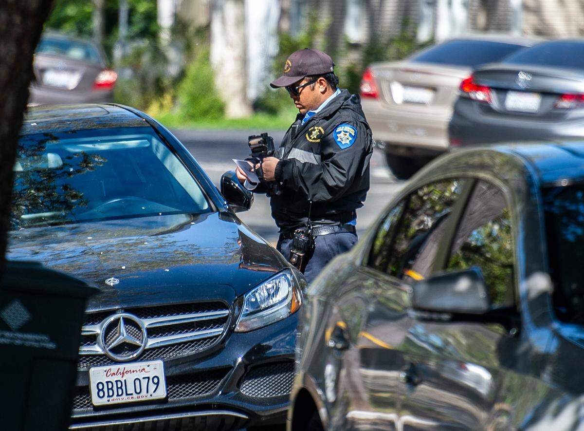A parking enforcement officer issues a warning for a car parked on 24th Street in midtown Sacramento in 2020. 
