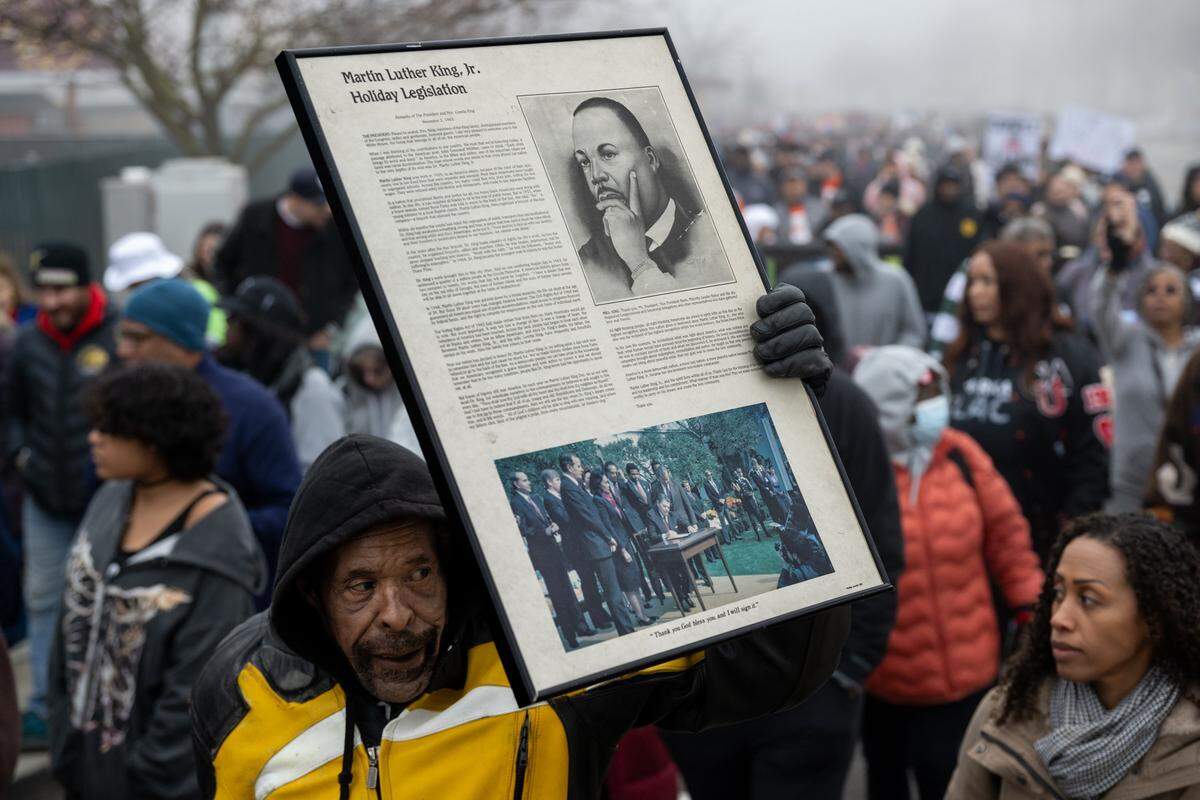 A marcher carries a portrait of the Rev. Martin Luther King Jr. during the Martin Luther King Jr. “Walk With Me” event at Sacramento City College on Monday.