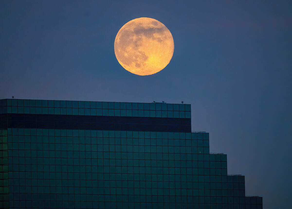 A supermoon climbs over the Emerald Tower at 300 Capitol Mall in downtown Sacramento at dusk on Thursday. It’s the last full moon of the year.