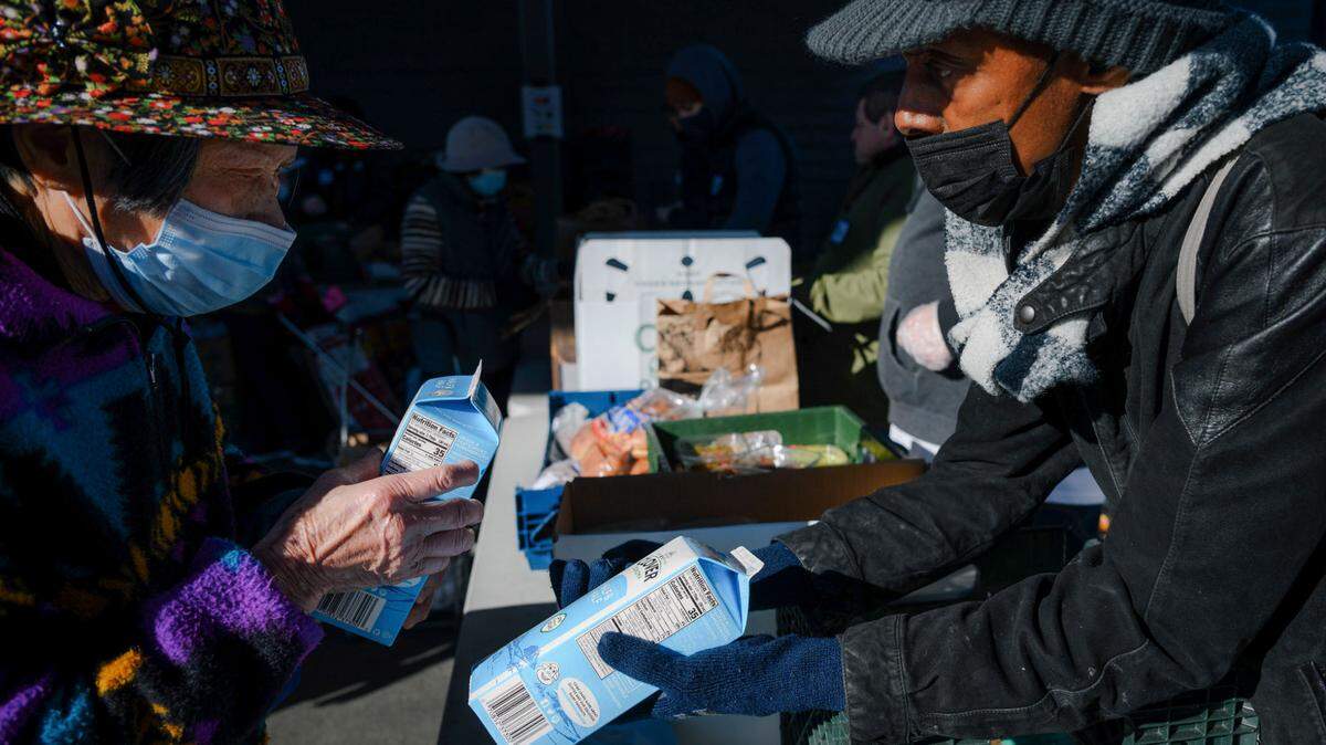 Volunteer Chalandis Adams, right, hands two cartons of milk to a senior customer at River City Food Bank in Sacramento last December.