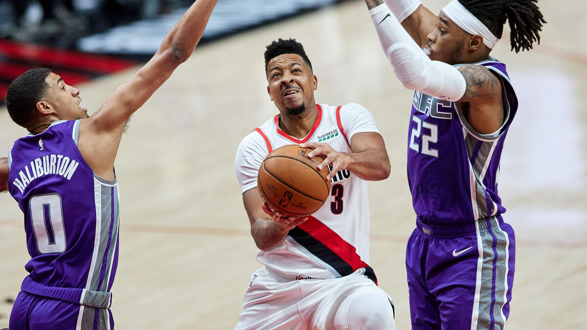 Portland Trail Blazers guard CJ McCollum, center, shoots between Sacramento Kings guard Tyrese Haliburton, left, and center Richaun Holmes during the first half of a preseason NBA basketball game in Portland, Ore., Friday, Dec. 11, 2020. (AP Photo/Craig Mitchelldyer)