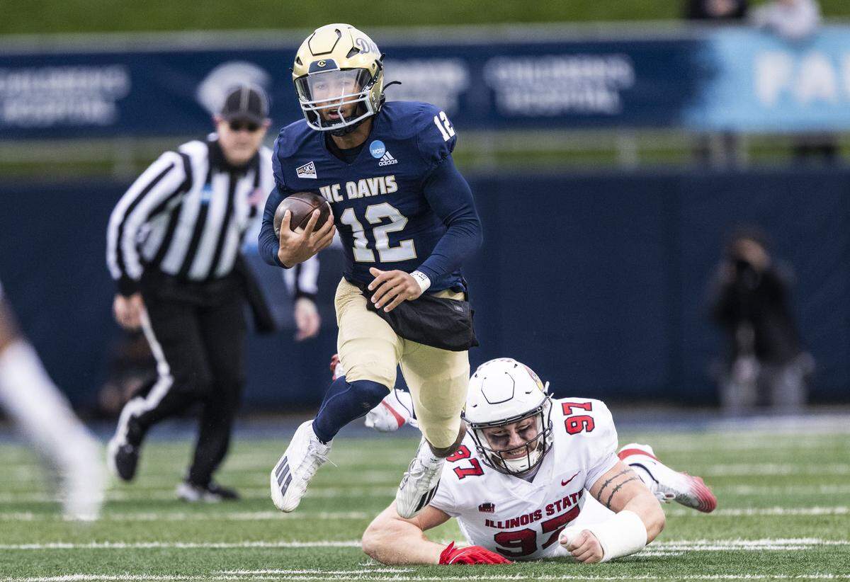 UC Davis Aggies quarterback Caden Pinnick is tripped by Illinois State Redbirds defensive lineman Jake Anderson during an FCS playoff quarterfinal at UC Davis Health Stadium on Saturday.