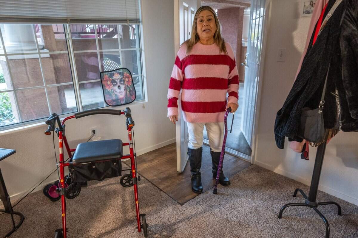 Dolores Mora holds a cane as she stands next to her walker in her Natomas apartment last month. A Medi-Cal recipient, she said that River City Medical Group helped her get those items and connected her with a nonprofit to find a safer housing environment that improved her health in other ways. Mora, who said her back pain can become debilitating, worked in farm fields as a child and later as an adult in convalescent homes as a certified nursing assistant.