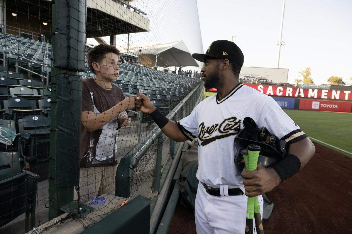 The Sacramento River Cats’ Osleivis Bassabe speaks with Dylan, a young baseball fan, after signing an autograph for him before a game earlier this month at Sutter Health Park.