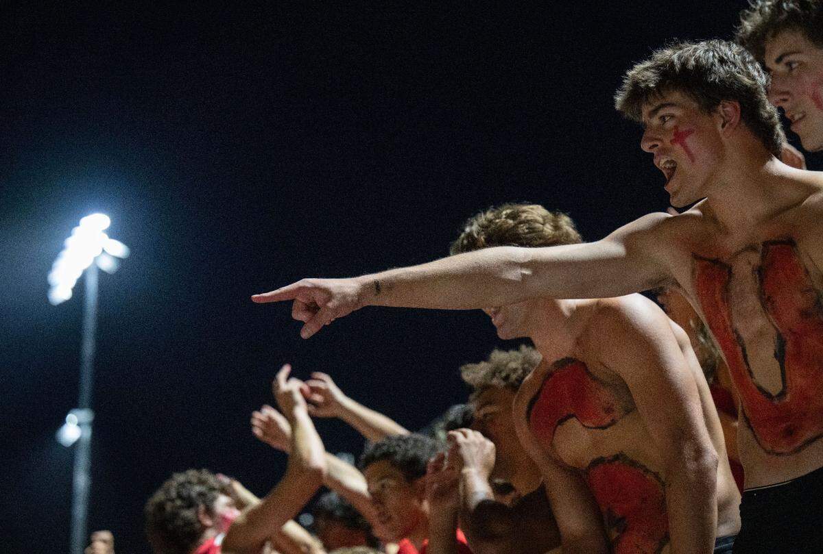 Jesuit student Owen Carmichael, his chest painted with the “U” from his school’s name, cheers on his team as the stadium’s new lights glow on Friday at Jesuit High School in Carmichael. It was the school’s first game with the permanent lights.