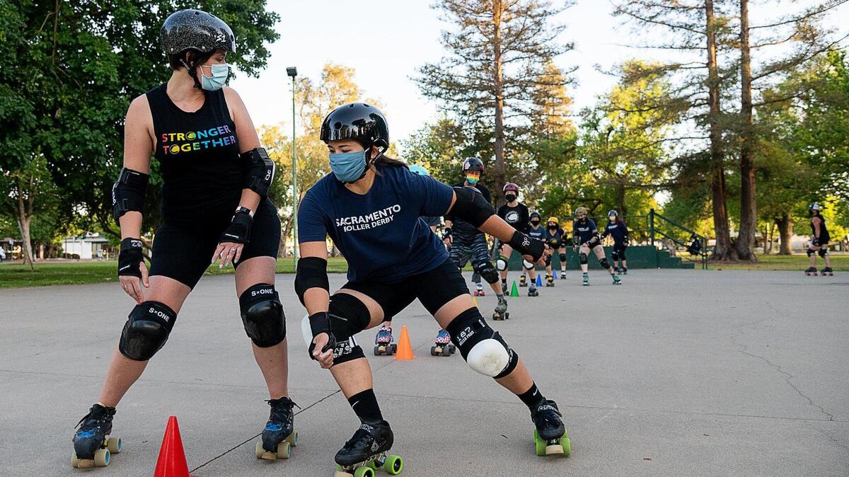 Sacramento Roller Derby Director of Coaching Judith Licciardello, aka “Rhodes Warrior,” left, leads practice on a concrete pad at Sacramento’s William Land Park on Monday, May 17, 2021. The Sacramento Derby has a wide age group of skaters.