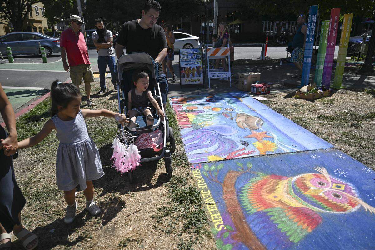 Festival attendees look at completed chalk drawings during Chalk It Up art festival at Fremont Park in Sacramento on Sunday.