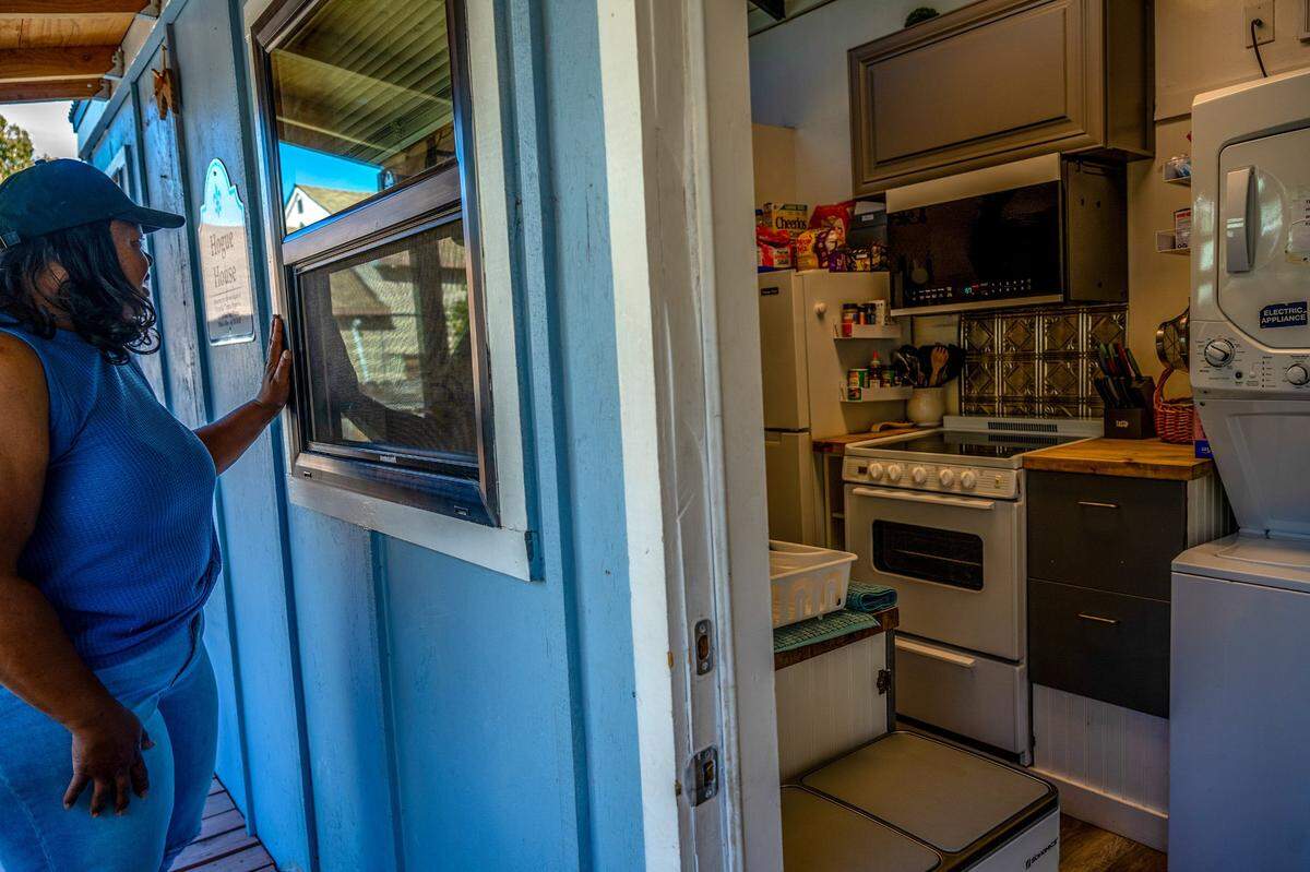 Robin Moore peers earlier this month into a community kitchen and laundry facility at Safe Harbor tiny home community she and her husband James created in their back yard. Moore has sheltered 37 families since she built the homes almost three years ago in her backyard.
