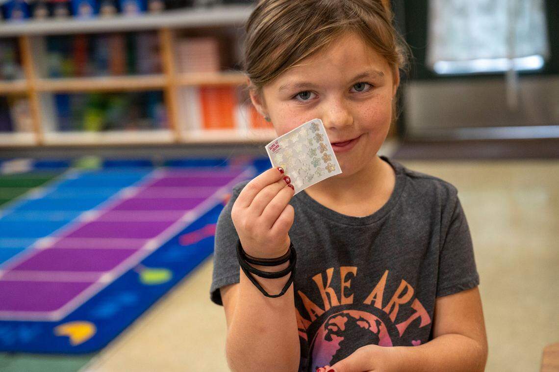 First-grader Theo holds up stickers to place in her workbook after working with a Sight Word Buster volunteer at Sierra Hills School in Meadow Vista earlier this month.