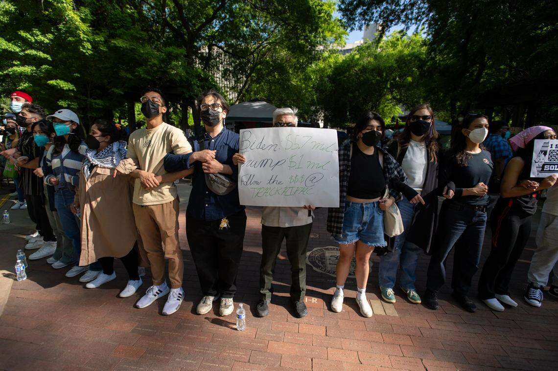 Pro-Palestinian activists lock arms on Tuesday, April 30, 2024, outside their tent encampment at Sacramento State as a counter-protester antagonized the group. The protesters are asking the university to divest from investments in Israel.