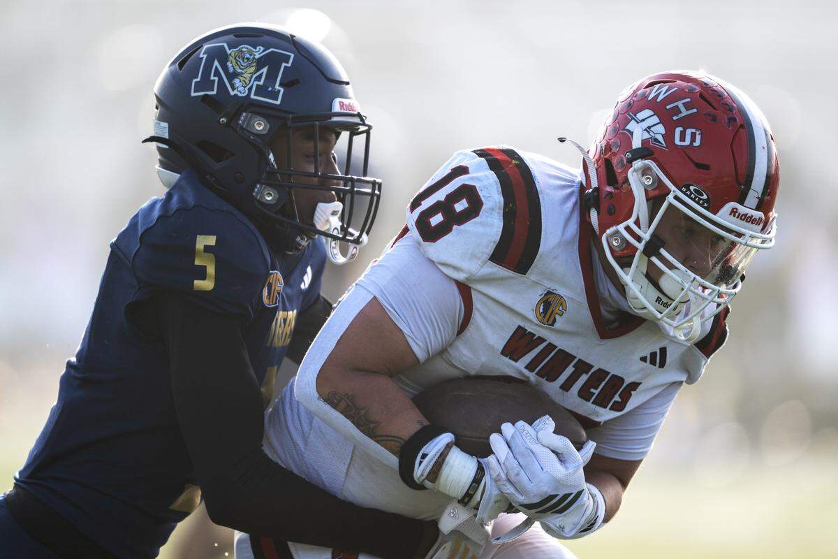The Winters Warriors' Anthony Matamoros (18) is tackled by the Morse Tigers' Rayvon Steward (5) as he scores a touchdown in the first half of the CIF Division 6-A State Championship football game at Buena Park High School in Buena Park on Saturday.