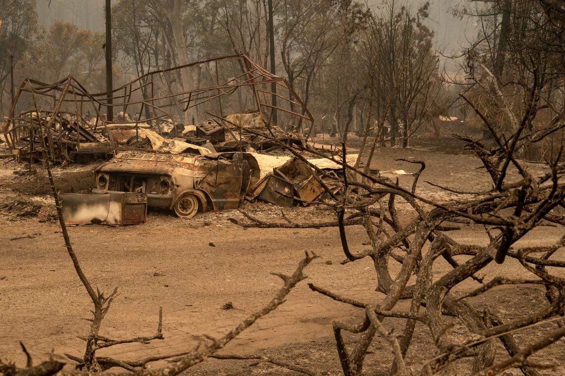 A burned vehicle and the frame of a house sit at the Oaks Mobile Park along Highway 96 as the McKinney Fire burns in Klamath National Forest in Siskiyou County on Sunday.