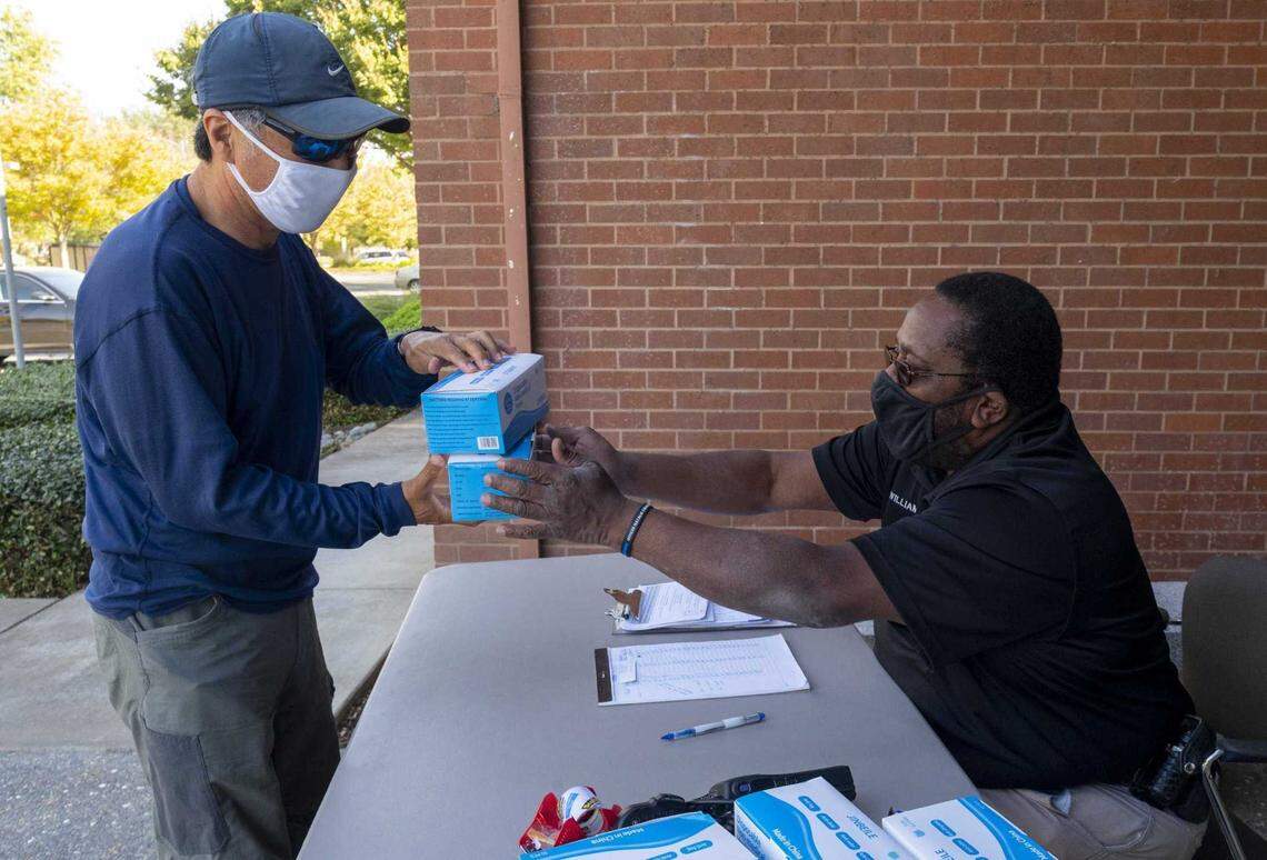 Son Chong, left, picks up free boxes of disposable masks from Kemper Williams at the Davis Police Department on Oct. 22, 2020. As part of the Healthy Davis Together initiative, the city of Davis joined with UC Davis to provide the masks to city residents and businesses to slow the spread of COVID-19.