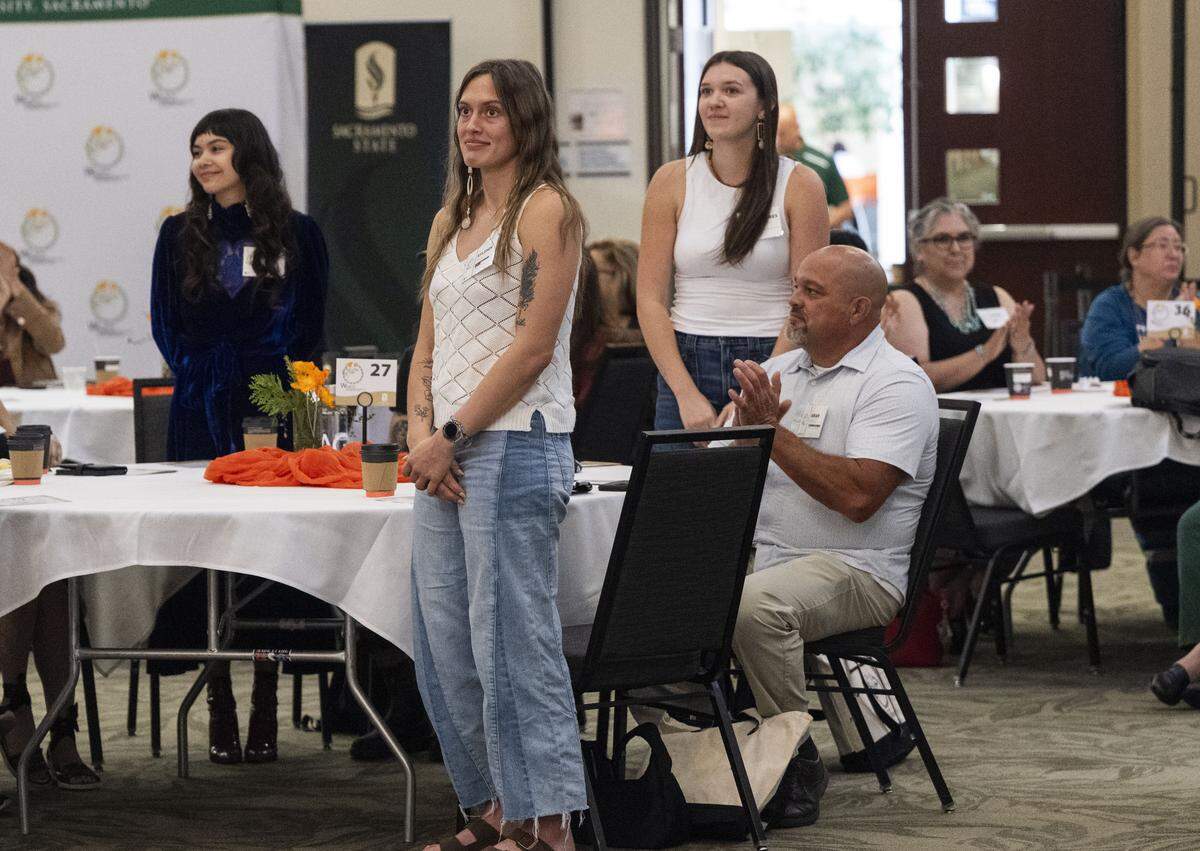 Students Ryleigh Hart, center, a member of the Susanville Indian Rancheria, and Neyr-Ress Bartoo, a Yurok tribal member, stand as they are acknowledged as part of the inaugural cohort to attend Wileety Native American College at Sacramento State during a grand opening event on Wednesday.