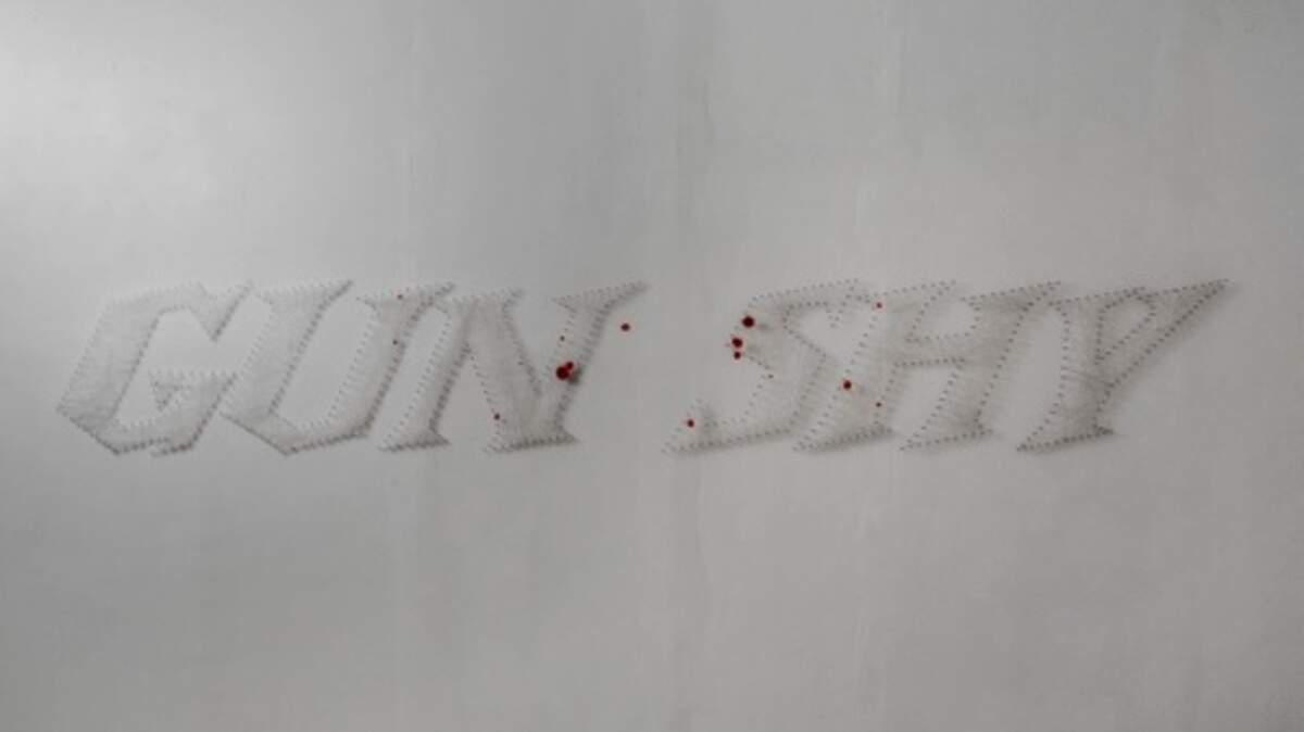 Julia Couzens’ ”Gun Shy” is made of small silver nails precisely wrapped with layers of almost invisible string placed to resemble the font used as a logo in ads for Winchester rifles.