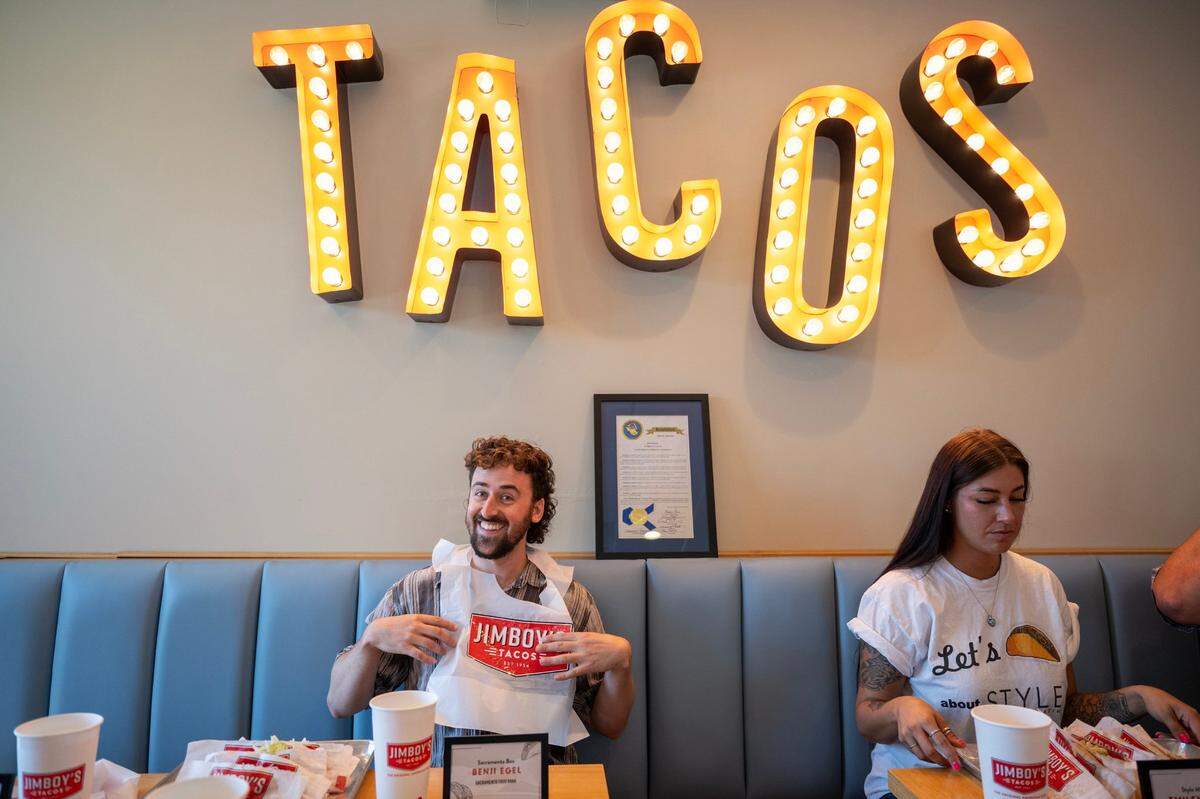 The Sacramento Bee’s food writer Benjy Egel puts on his bib next to Style Magazine’s Emiley Mohr before the Jimboy’s Tacos Eating Contest on Wednesday in Folsom.