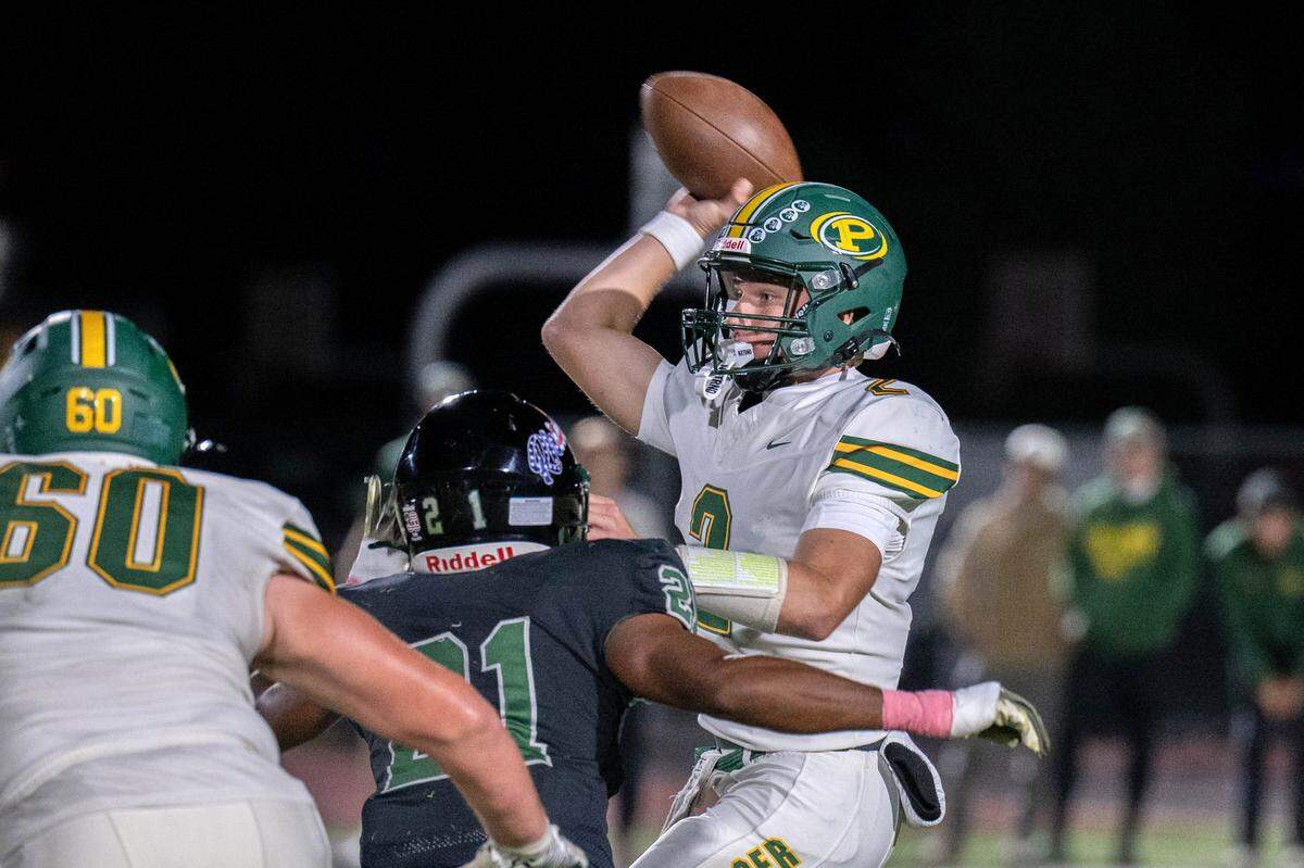 The Placer Hillmen's Chase Rodarte (2) is hit by the Twelve Bridges Raging Rhinos' Cordae Johnson (21) as he releases the ball in the first half on Friday in Lincoln.