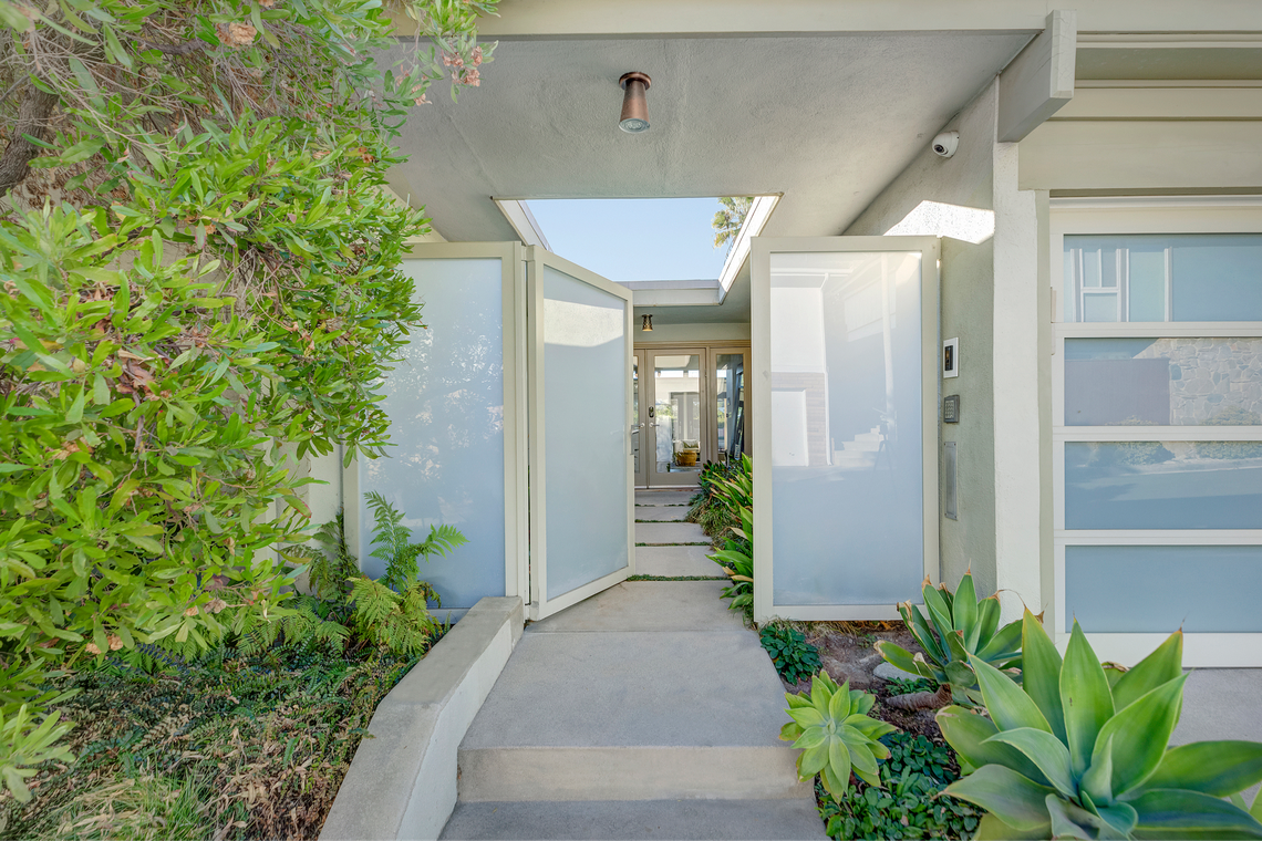 A dramatic runway-style entrance framed by lush greenery leads to a tropical atrium.