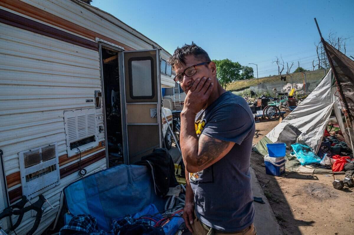 Erick Read, 48, stands near a camper he is living in along Lathrop Way in Sacramento on April 21 and shares how he became homeless when he lost his restaurant job during the pandemic. “We were in South Natomas and cops evicted us from that spot and told us to come here,” said Read. “I’d like to get a job and pay rent somewhere. That’s all I want in life.”