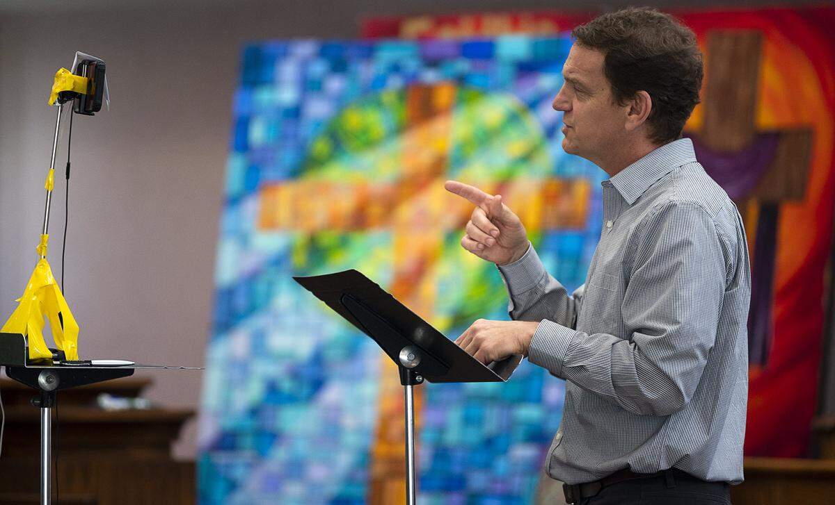 Jeff Chapman, pastor of Faith Presbyterian Church where two members have died from COVID-19, uses his iPhone to record an online service to an empty chapel Sunday, April 26, 2020, in Sacramento. The church closed to on March 12 prevent the spread of coronavirus after some congregants developed symptoms.