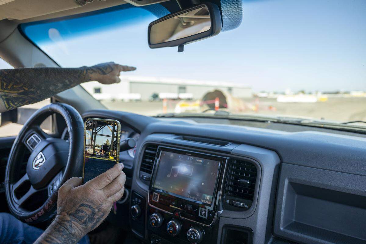Tim Campbell, president of International Longshore and Warehouse Union Local 18, points to the remains of an underground woodchip conveyor belt at the Port of West Sacramento on Thursday, July 31, 2025, that was decommissioned and destroyed in February 2025. On his phone, Campbell pulls up a photo of what it looked like before it was demolished.