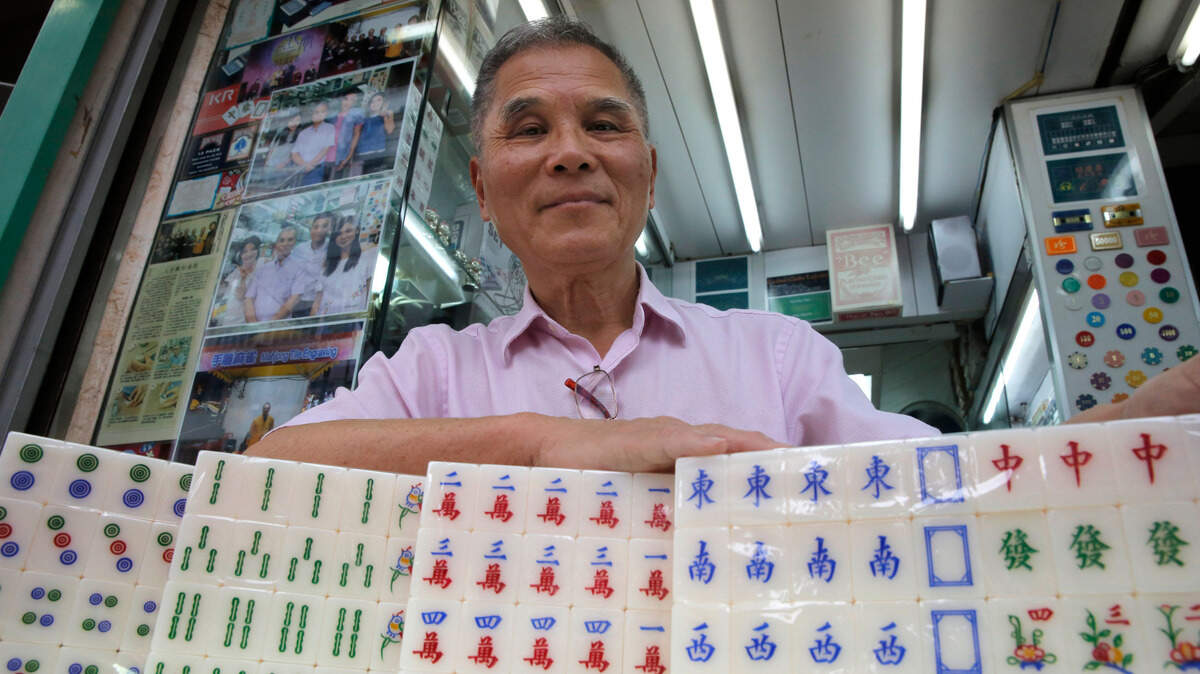 Cheung Shun-king shows off the mahjong game he created in Hong Kong. A company owned by white women has been criticized for changing the tiles from the traditional Chinese symbols to things like bubbles and palm trees.