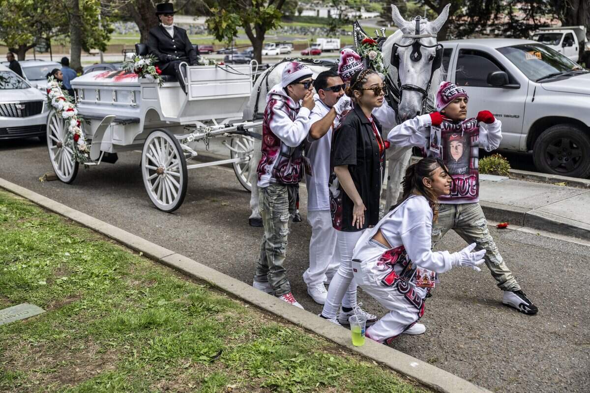 Jhanelly, the sister of Jesus and Jhony Ramos, bottom right, poses for a photo with other mourners in front of a horse-drawn carriage carrying the casket of Jesus on Monday in Greenlawn Memorial Park in Colma.