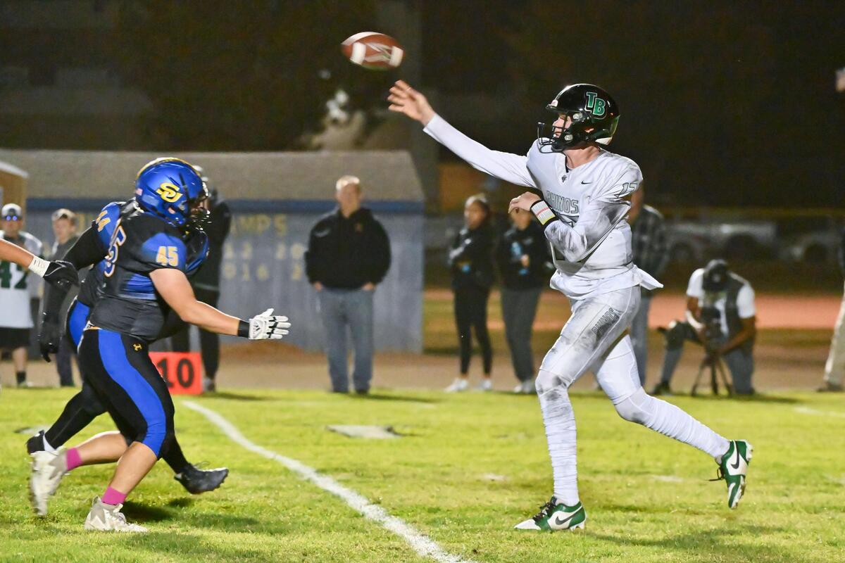 Twelve Bridges Raging Rhinos quarterback Whit Kruse (17) passes to wide receiver Brayden Wooster for an 18-yard gain in the first half against the Sutter Huskies on Thursday at Sutter Union High School.