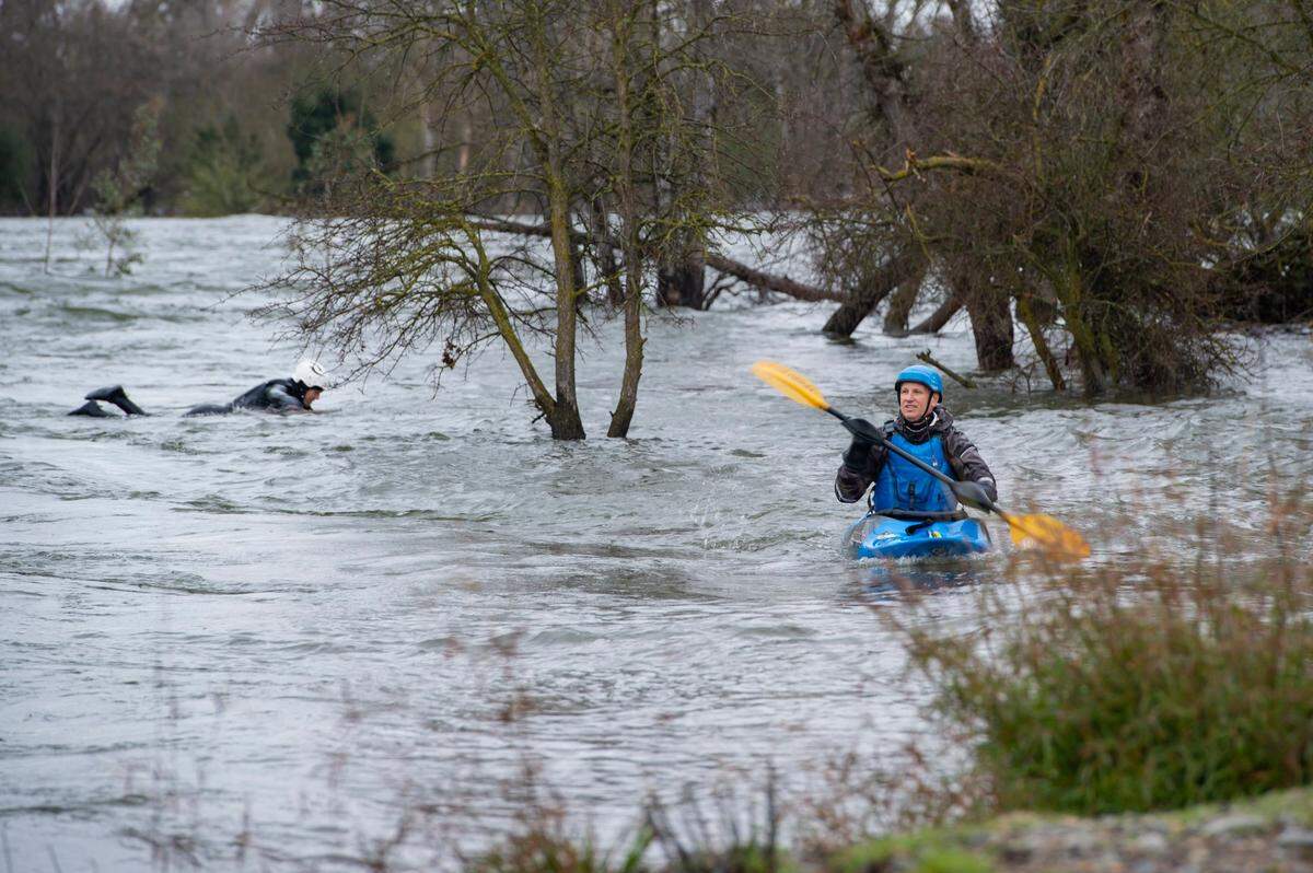 A kayaker comes inland while Tyler Lausten, left, uses the eddy to avoid dangers downstream after river surfing on Sunday, March 12, 2023, in the American River near Carmichael.