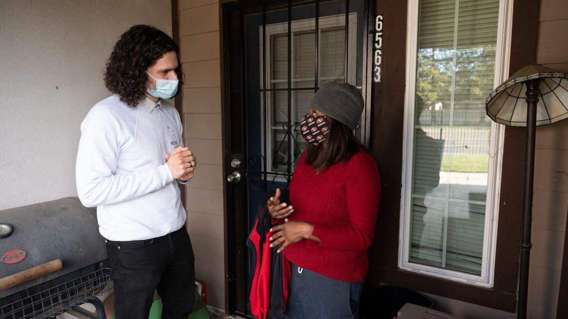 Fienishia Wash habla con Cameron Collins en el porche de su casa, en el sur de Sacramento, el 22 de enero de 2022. Wash es beneficiaria del primer programa de pagos directos de Sacramento, en el que 100 familias reciben $300 al mes. Collins participa en el Programa de Inversión Directa en Sacramento (DIPS) a través de United Way.