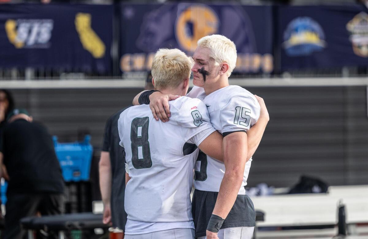 The Twelve Bridges Raging Rhinos’ Isaiah Rodriguez (8) and Connor Flaherty (15) comfort each other after their team’s 55-19 loss to Palos Verdes in the CIF State Division 2-A championship at Saddleback College in Mission Viejo on Saturday.