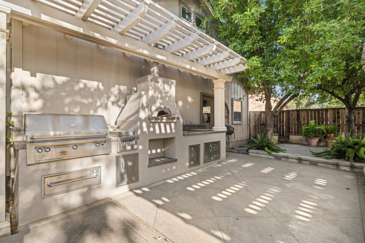 The outdoor kitchen has a pizza oven and covered patio.