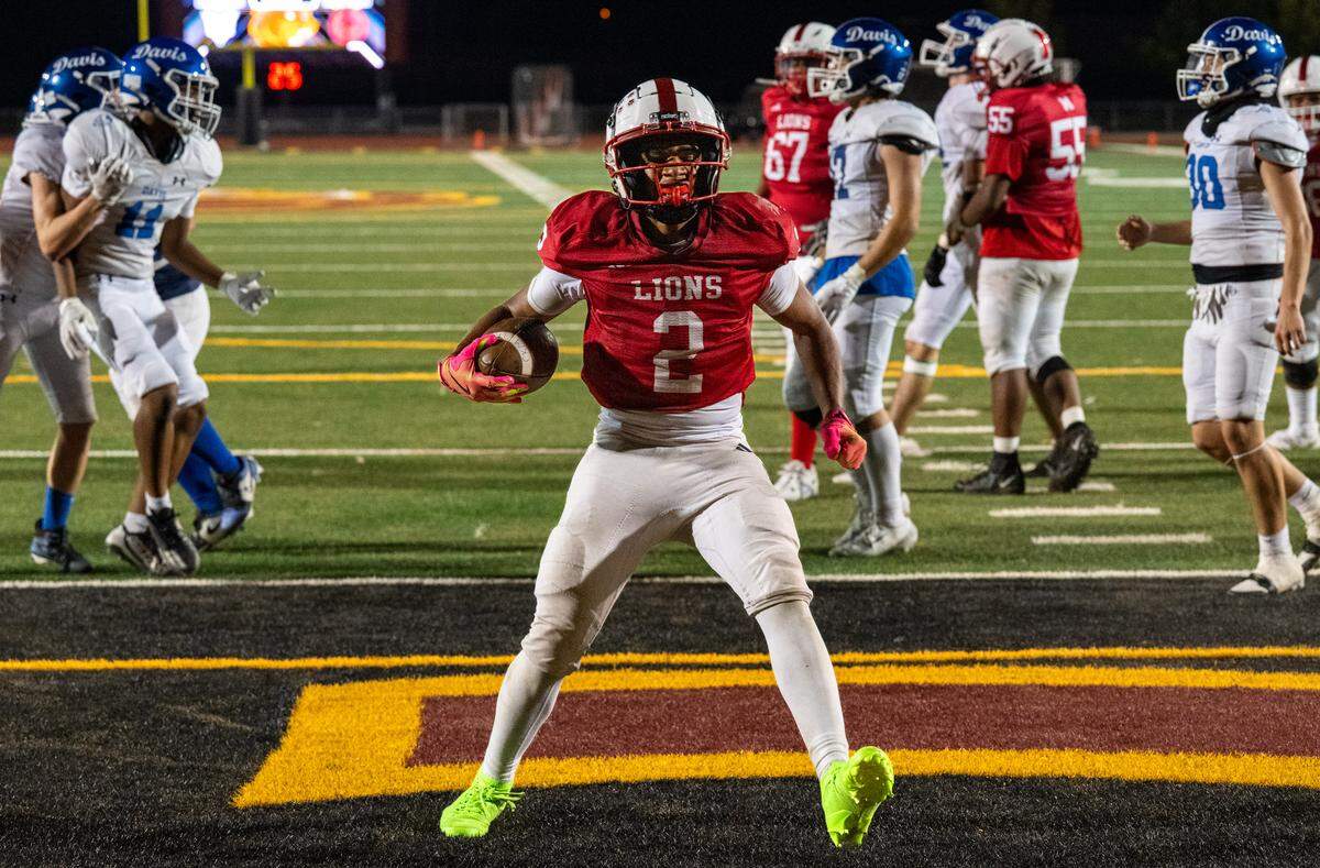 The McClatchy Lions' Robert Jackson III (2) scores his team’s final touchdown to retake the lead against the Davis Blue Devils on Friday at Hughes Stadium in Sacramento. 