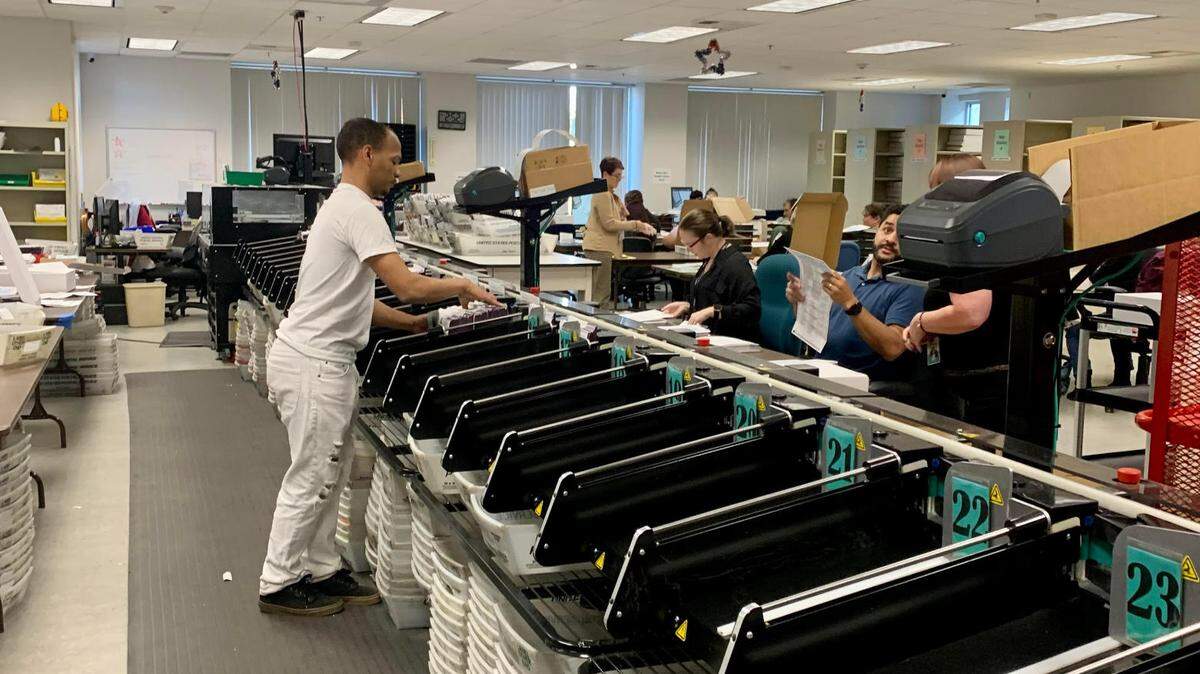 Staff at the Placer County Elections Office run mail-in ballots through their processing machine on Nov. 21, 2022.