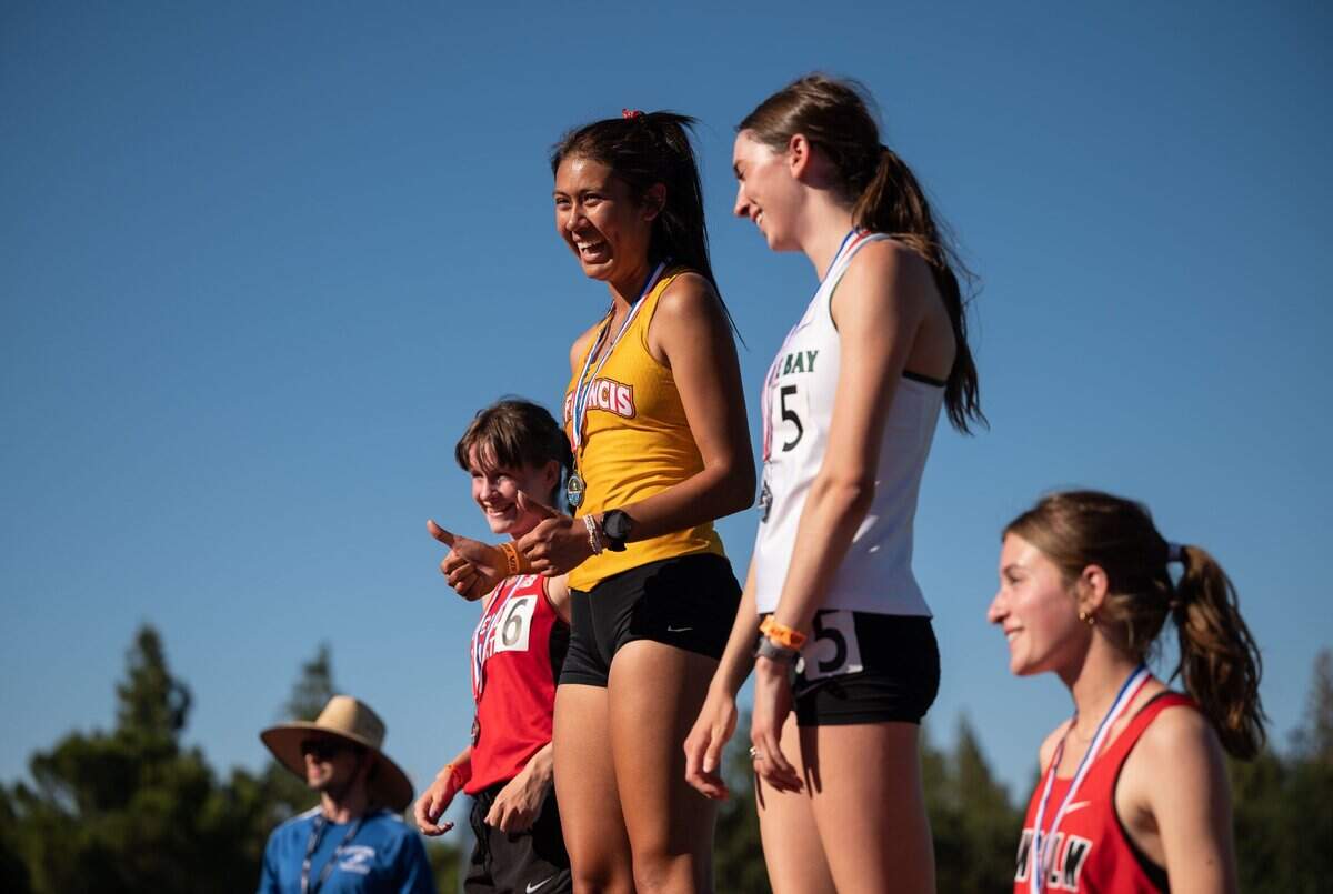 St. Francis’ Tatiana Cornejo, center, smiles and gives two thumbs up after she won the girls’ 1,600-meter run at the CIF Sac-Joaquin Section Masters track and field finals at Davis High School on Saturday.