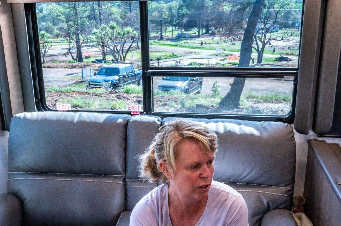 Lynn Grace, who lost her home to the Glass Fire in September, sits on a couch in a RV parked on her property in April with a view of her Sunnyside Road community in Napa County. Like many in the area, she and her husband want to rebuild, but the construction costs will be hundreds of thousands of dollars more than their insurance policy will pay.