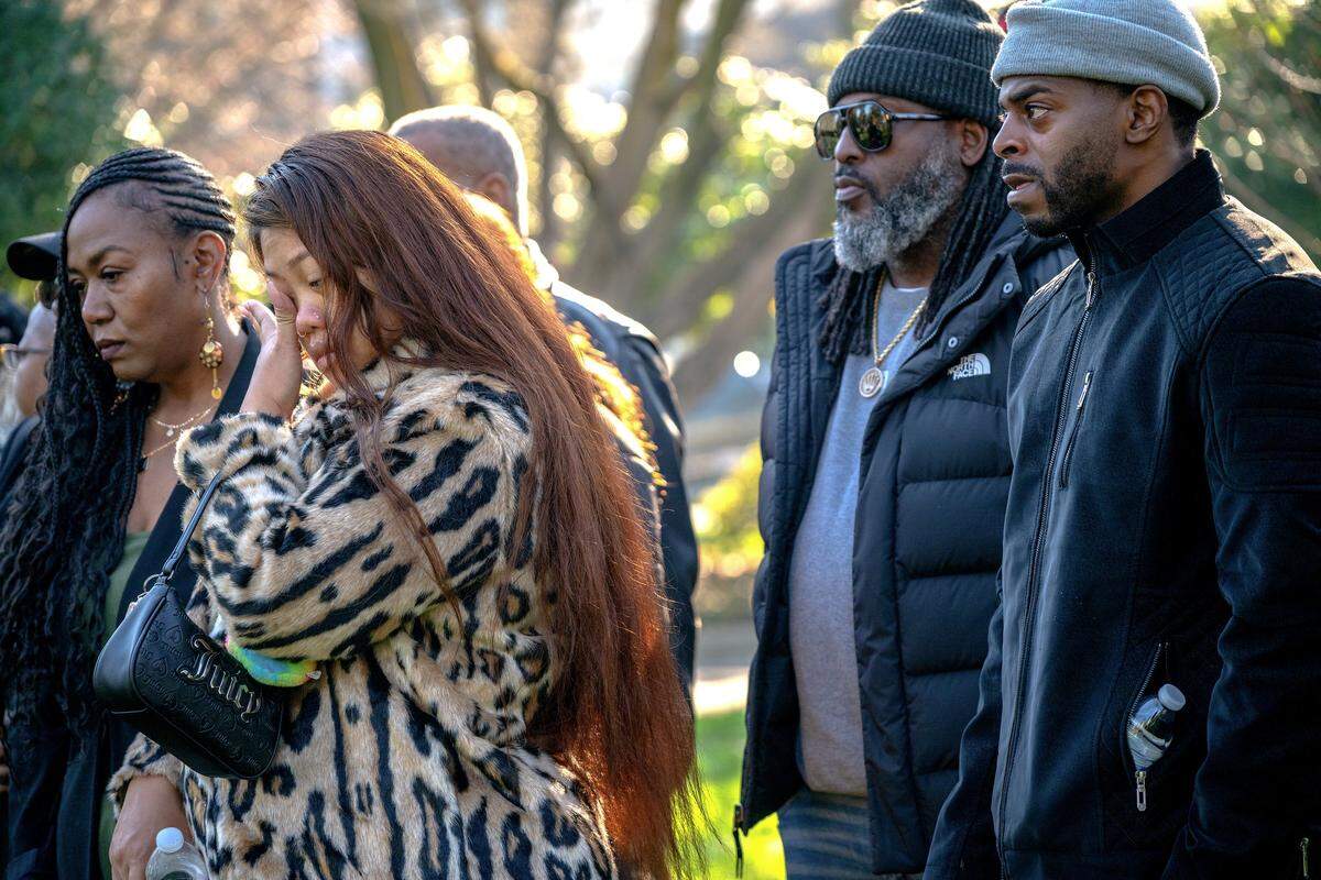 A woman wipes her tears next to Patrick Peterson, right, father of 14-year-old Amari Peterson who was killed in the Nov. 29 mass shooting, during an emotional press conference at Capitol Park in Sacramento on Tuesday.
