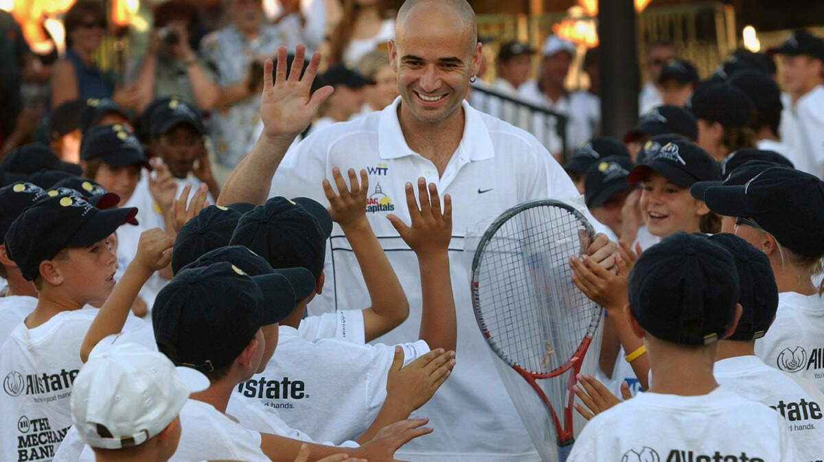 Tennis superstar Andre Agassi is greeted by ball boys and girls before playing for the Sacramento Capitals during a World Team Tennis match at Sunrise Mall on July 7, 2004.