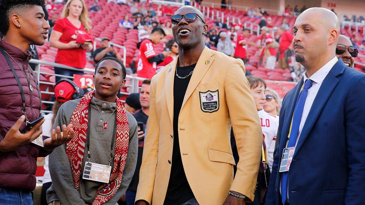 Former NFL wide receiver Terrell Owens, center, is shown before an NFL football game between the San Francisco 49ers and the Oakland Raiders in Santa Clara, Calif., Thursday, Nov. 1, 2018. (AP Photo/John Hefti)
