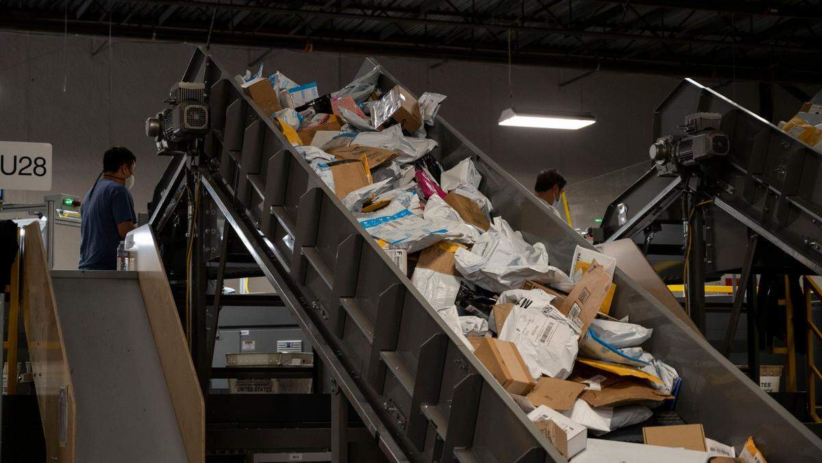 Postal workers scan packages on a small parcel sorting system at the Sacramento Processing and Distribution Center on Tuesday, Nov. 2, 2021, in West Sacramento.