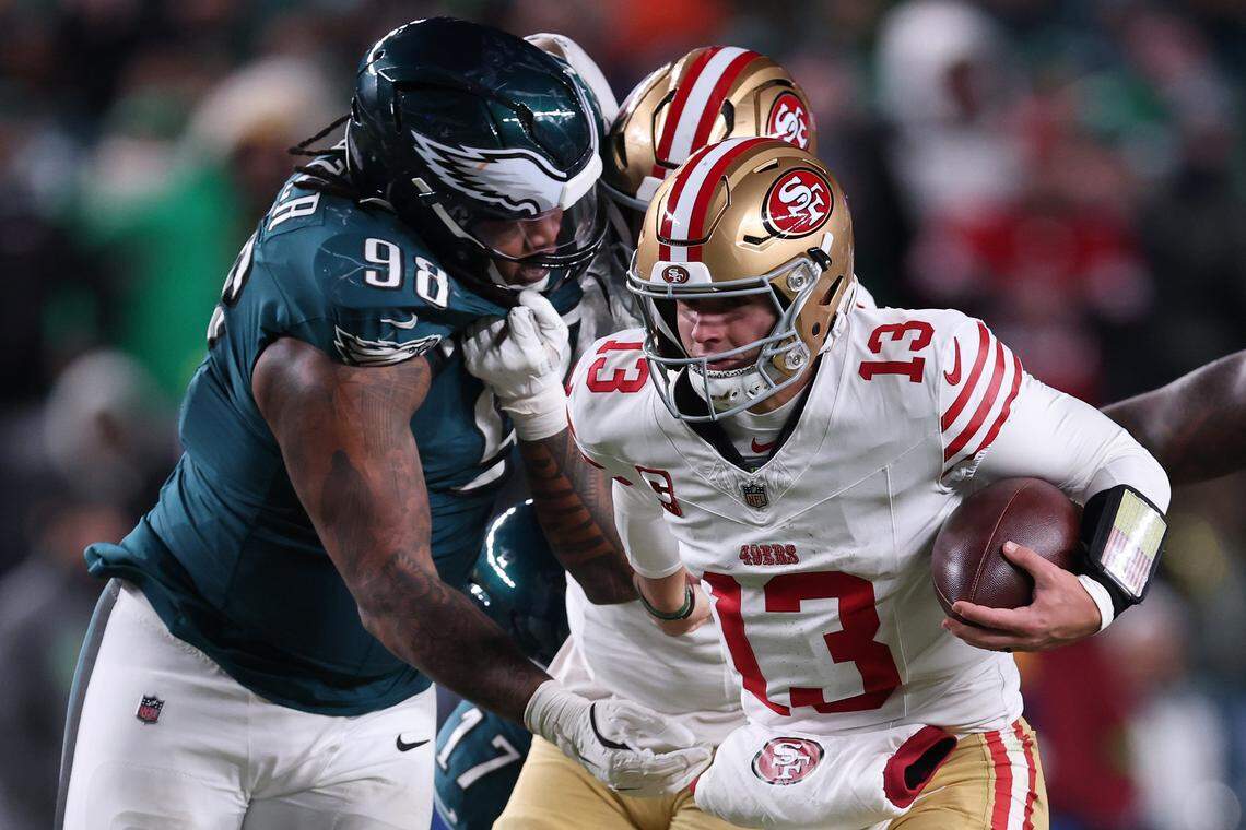 PHILADELPHIA, PENNSYLVANIA - JANUARY 11: Brock Purdy #13 of the San Francisco 49ers scrambles past Jalen Carter #98 of the Philadelphia Eagles during the fourth quarter in the NFC Wild Card Playoff game at Lincoln Financial Field on January 11, 2026 in Philadelphia, Pennsylvania. (Photo by Elsa/Getty Images)