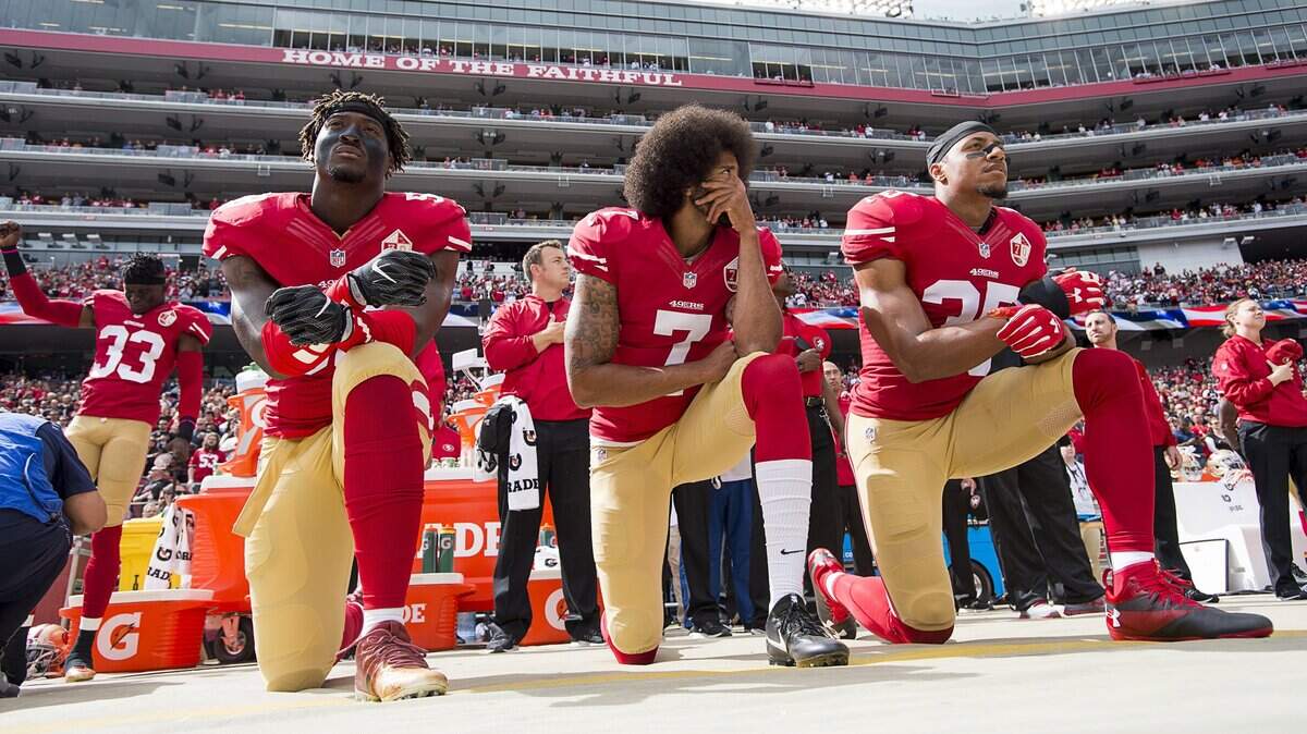 Colin Kaepernick, center, kneels with Eli Harold, left, and Eric Reid during the playing of the national anthem before the 49ers' game against the Dallas Cowboys on Oct. 2, 2016, in Santa Clara.