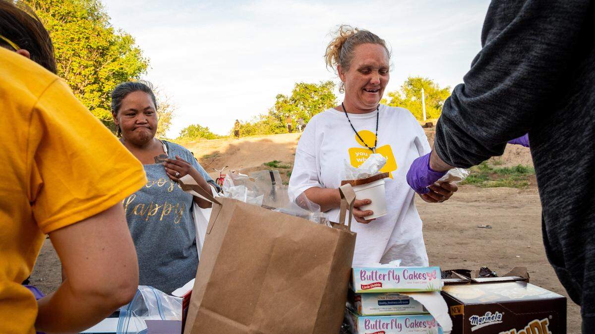 Amber Hamilton, center, is served by Nick Bennett during one of Sacramento SOUPs food distributions for unhoused people near a camp along the American River in 2020. Many taxpayers can get a bigger deduction this year for contributions to nonprofits. and charities