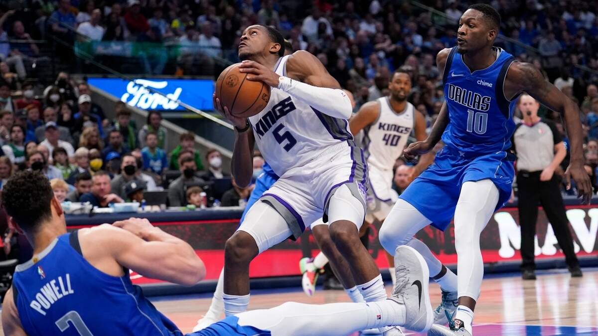 Dallas Mavericks center Dwight Powell (7) falls to the floor as he and forward Dorian Finney-Smith (10) defend against a shot attempt by Sacramento Kings guard De’Aaron Fox (5) in the second half of an NBA basketball game in Dallas, Saturday, March, 5, 2022. (AP Photo/Tony Gutierrez)