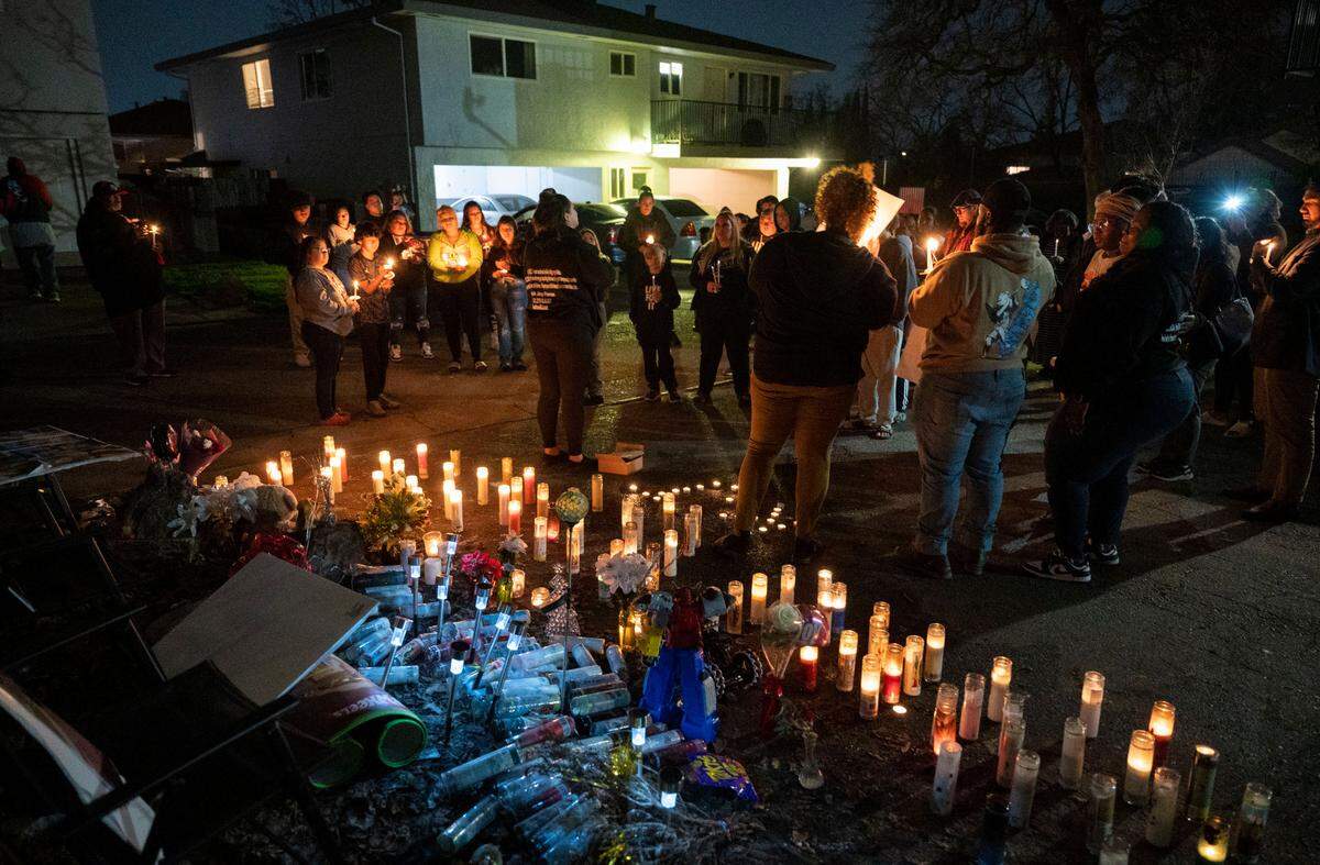 People hold candles during a vigil for Keith “KJ” Frierson on Tuesday in Foothill Farms, one month after he was shot and killed on Dec. 30 at the Hillsdale Oaks condo community where he lived.