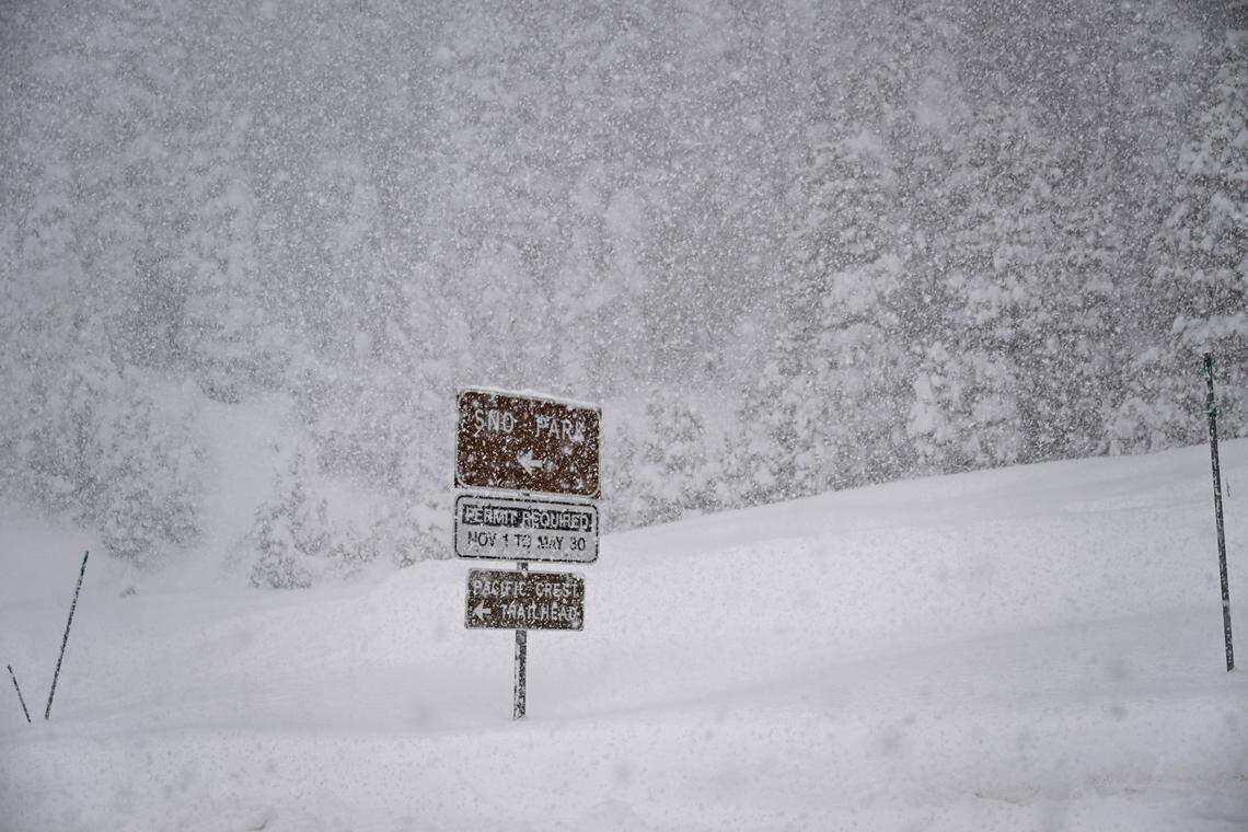 Falling snow obscures a sign for a Sno Park and a Pacific Crest Trail trail head on Interstate 80 on Thursday.